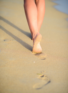 海滩旅行女人在留下脚印在沙滩上行走