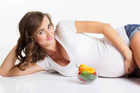 怀孕的女孩拿着板与蔬菜
