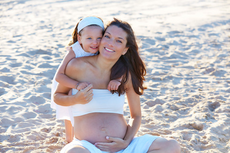 怀孕的母亲和女儿在海滩上