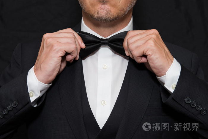 戴着黑色领带绅士直他的领结