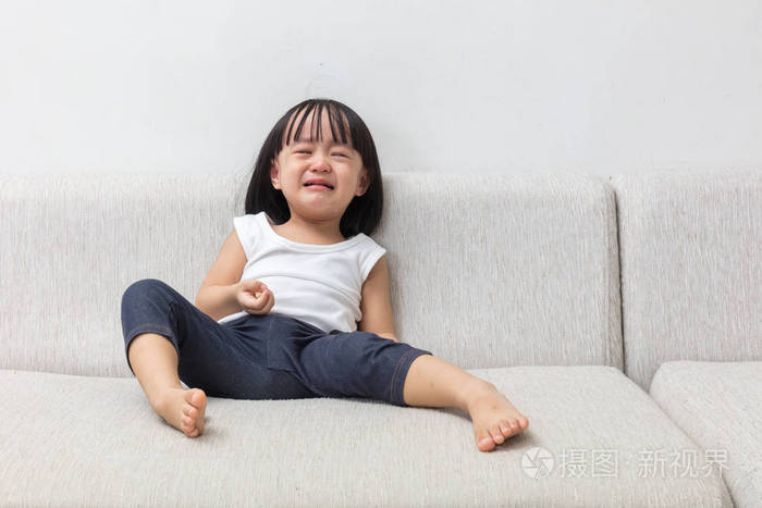 亚洲中国的小女孩正坐在沙发上哭了起来照片-正版商用