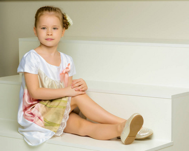 美丽的小女孩坐在白色的楼梯上