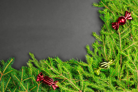 顶视图的绿色新鲜冷杉的枝条和装饰品，在糖果帧的形式在一个黑色的背景上。圣诞节，新的一年。Copyspace