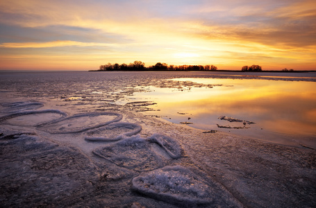 冬季景观与湖和落日的天空。自然的组成