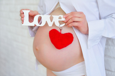 怀孕的妇女抱着爱情的标志