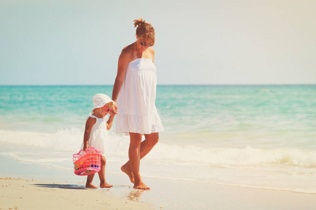 母亲和可爱的小女儿，在海滩上行走