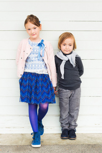 白色的木墙上的两个时尚孩子。