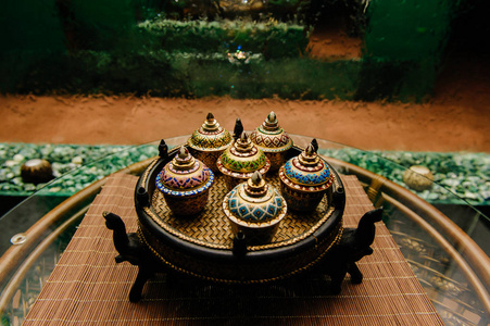 传统的泰国著名瓷 benjarong 陶瓷装饰与大象站在藤表与玻璃表面与抽象的背景墙上下降水碗柳条板上。仪式