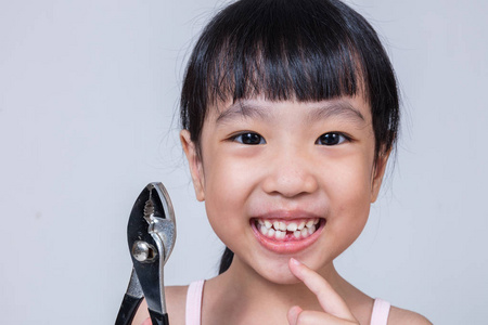 亚洲中国的小女孩拿着钳子和显示差距