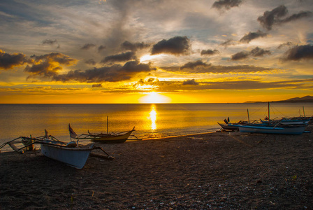在海滩上美丽的夕阳。站在岸边的本地船只。香兰，班乃菲律宾
