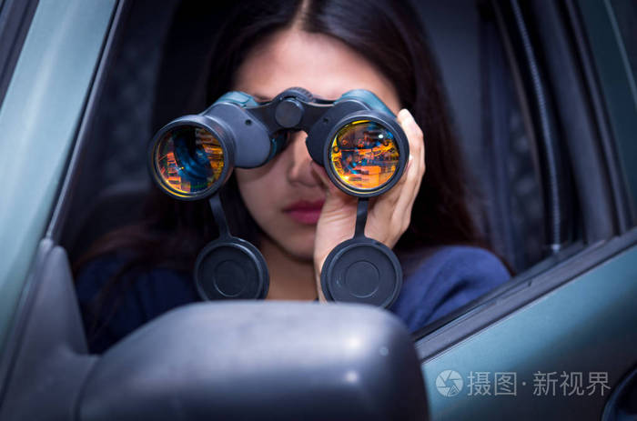 年轻的女人用她的车内黑色双筒望远镜跟踪