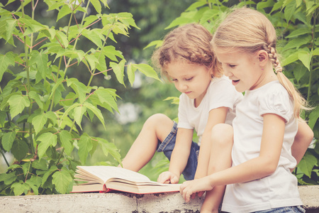 小男孩和女孩坐在公园的书