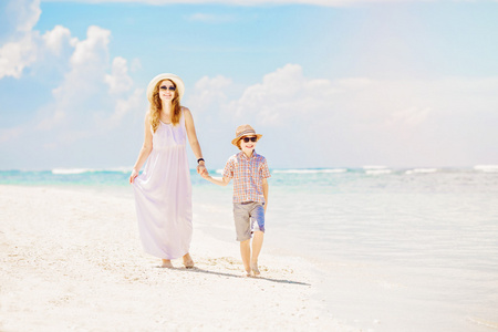 母亲和儿子沿着白沙滩散步，有一个大家庭
