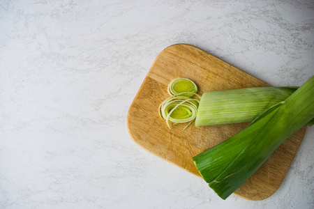 烹饪健康的食物。切片和切碎的韭菜炒木菜板孤立在白色背景上的绿色沙拉