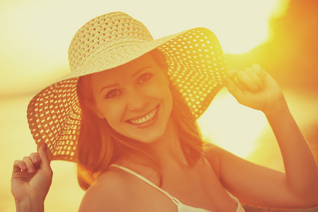 在海上日落海滩上的帽子美幸福微笑的女人
