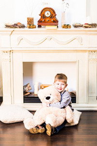 可爱的男孩，附近圣诞树上的玩具熊的肖像