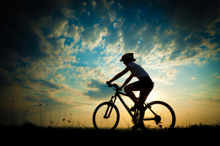 骑自行车的女孩在草地上日落