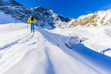 走上沿与白雪皑皑的山脊的登山野外滑雪