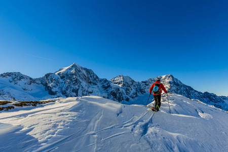 走上沿与白雪皑皑的山脊的登山野外滑雪