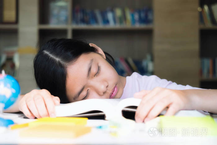 疲倦的学生女孩睡在桌子上的书.教育