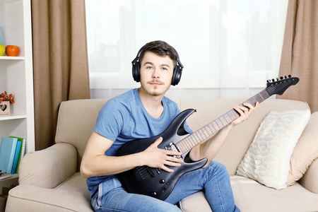 吉他在房间里的沙发上的年轻人