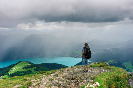 背包的在山顶上的雨和远方期待的山脉和美丽的绿松石山 lake,Alps,Austria.Breathtaking 视图的山