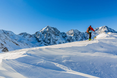 走上沿与白雪皑皑的山脊的登山野外滑雪