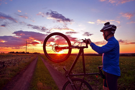 双臂在日落时举起自行车骑自行车的人