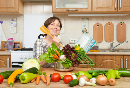 烹饪蔬菜汤的女人。家用厨房室内。健康食品的概念