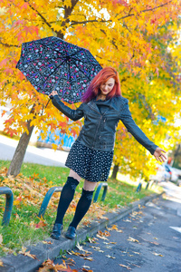秋天的场景中的伞的漂亮女孩
