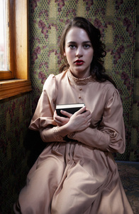20 世纪初坐米色复古服饰的年轻女子