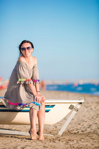 年轻漂亮的女人在暑假期间的海滩上。坐在船上欧洲海滩上的女孩