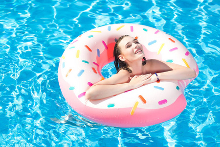 白种人白美丽少妇放松在游泳池里。女孩游泳与橡胶圈，微笑着，在游乐园玩。暑假和活跃节日概念