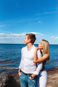 幸福的夫妇的海面背景。快乐的年轻夫妇笑着拥抱在沙滩上