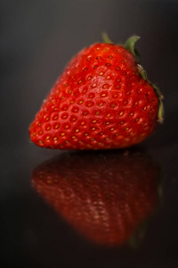 红色的草莓，黑色有光泽背景与反射