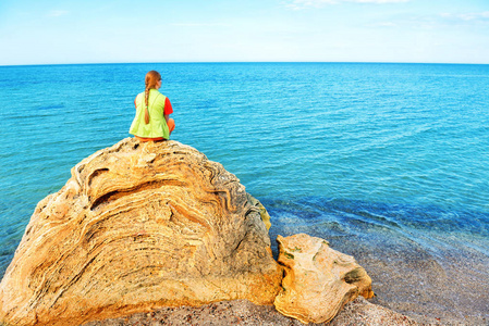年轻的女人坐在一块大石头上