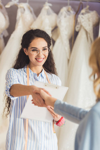 女裁缝与新娘在婚纱店握手