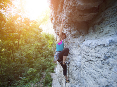 年轻女人用绳子爬上岩石