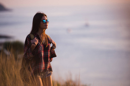 女性旅行者在日落时分看海上湾的背景山悬崖的边缘