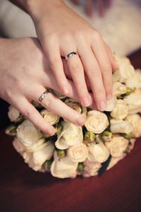 新郎和新娘结婚戒指与从玫瑰婚礼花束手