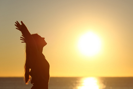 女人在日落时呼吸新鲜空气图片