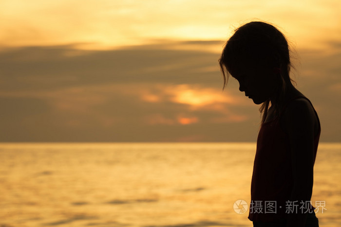 悲伤的金发小女孩站在海滩上的肖像