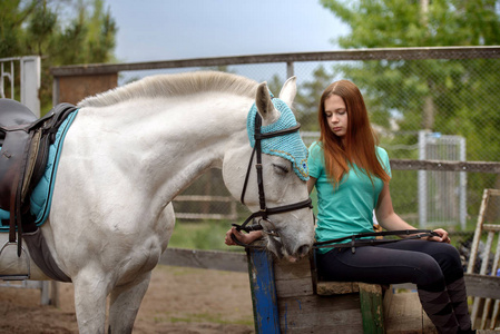 女孩的骑手和她的马在马厩附近骑马后休息