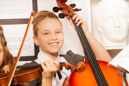 小女孩微笑着持有大提琴