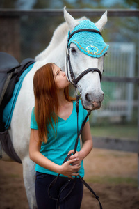 女孩的骑手和她的马在马厩附近骑马后休息
