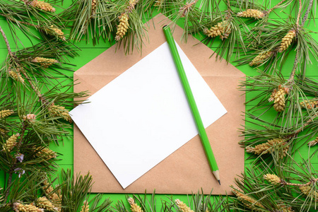 一张空白的纸信封在松枝上绿色的木制背景