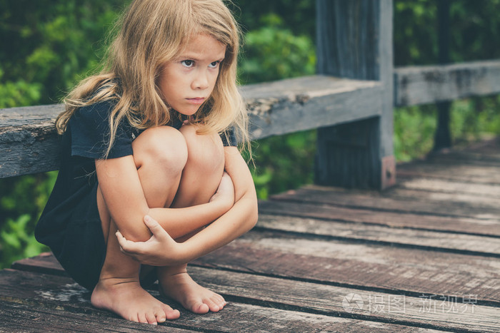 坐在桥上悲伤的金发小女孩的肖像