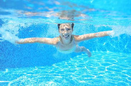 快乐的女孩游在水下，游泳池游泳 踢球和玩乐的好动小孩，儿童水运动