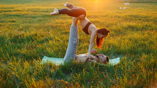 夫妇在日落时练习瑜伽。健康的生活方式的概念