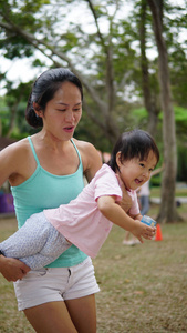 亚洲女人携带幼儿和参与家庭游戏户外